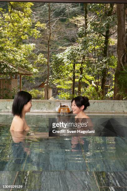 happy young women talking and soaking in onsen pool - sven hagolani stock-fotos und bilder