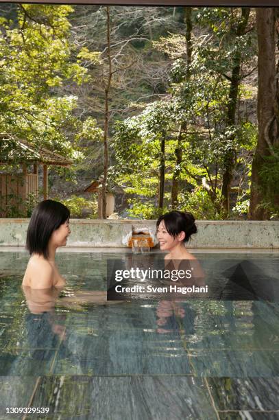 happy young women talking and soaking in onsen pool - sven hagolani stock pictures, royalty-free photos & images