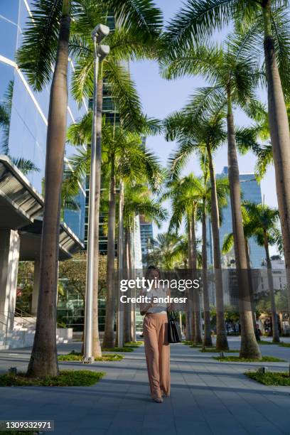 real estate agent using her cell phone while walking on the street - miami business stock pictures, royalty-free photos & images