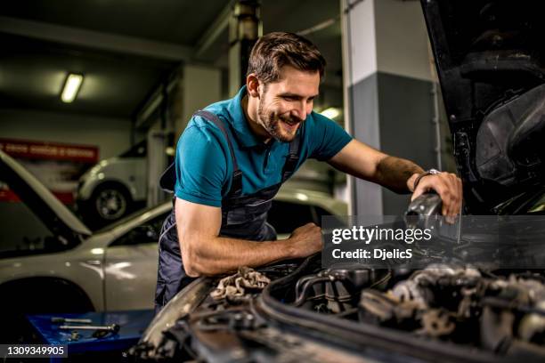 mechanic changing oil on the vehicle at car workshop. - oil change stock pictures, royalty-free photos & images