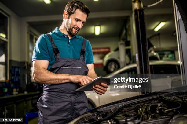 快樂的機械師在汽車修理店的數位平板電腦上檢查汽車診斷。 - 機械工人 個照片及圖片檔