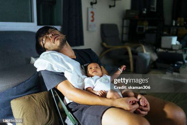 young adult  asian father is holding his crying baby daughter on his chest and baby crying in the night times - good times stock-fotos und bilder