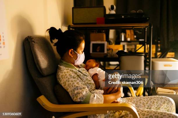 young adult  asian mother is holding her daughter and feeding the night times - moms crying in bed stockfoto's en -beelden