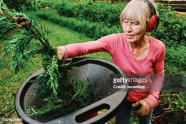 mujer usando trituradora eléctrica en jardín - orejeras fotografías e imágenes de stock