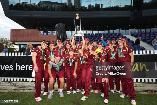 The Queensland Fire players celebrate with the trophy in front of fans after winning the WNCL Final match between Victoria and Queensland Fire at...