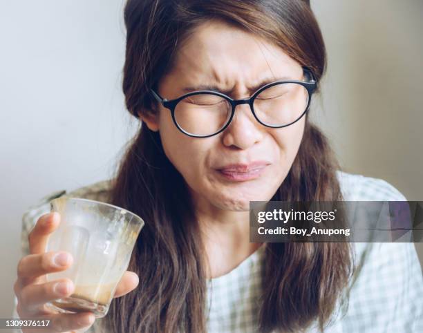 facial expression of young asian woman after drinking strong coffee. - sabor amargo fotografías e imágenes de stock