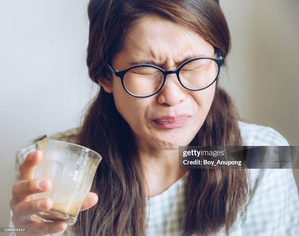 Facial expression of young Asian woman after drinking strong coffee.