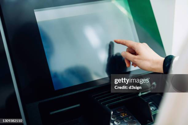 close up of young woman using automatic cash machine in the city. withdrawing money, paying bills, checking account balances, transferring money. privacy protection, internet and mobile security concept - interattività foto e immagini stock
