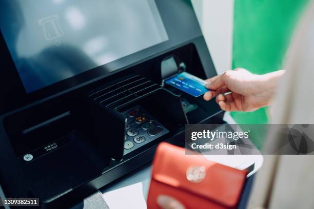 close up of young woman inserting her bank card into automatic cash machine in the city. withdrawing money, paying bills, checking account balances, transferring money. privacy protection, internet and mobile security concept - bank sign ストックフォトと画像