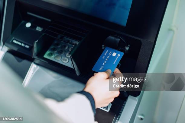 close up of young woman inserting her bank card into automatic cash machine in the city. withdrawing money, paying bills, checking account balances, transferring money. privacy protection, internet and mobile security concept - conto corrente foto e immagini stock