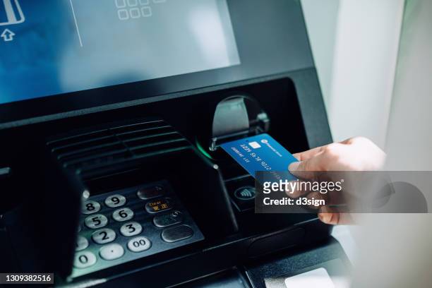 close up of young woman inserting her bank card into automatic cash machine in the city. withdrawing money, paying bills, checking account balances, transferring money. privacy protection, internet and mobile security concept - atm screen stock-fotos und bilder