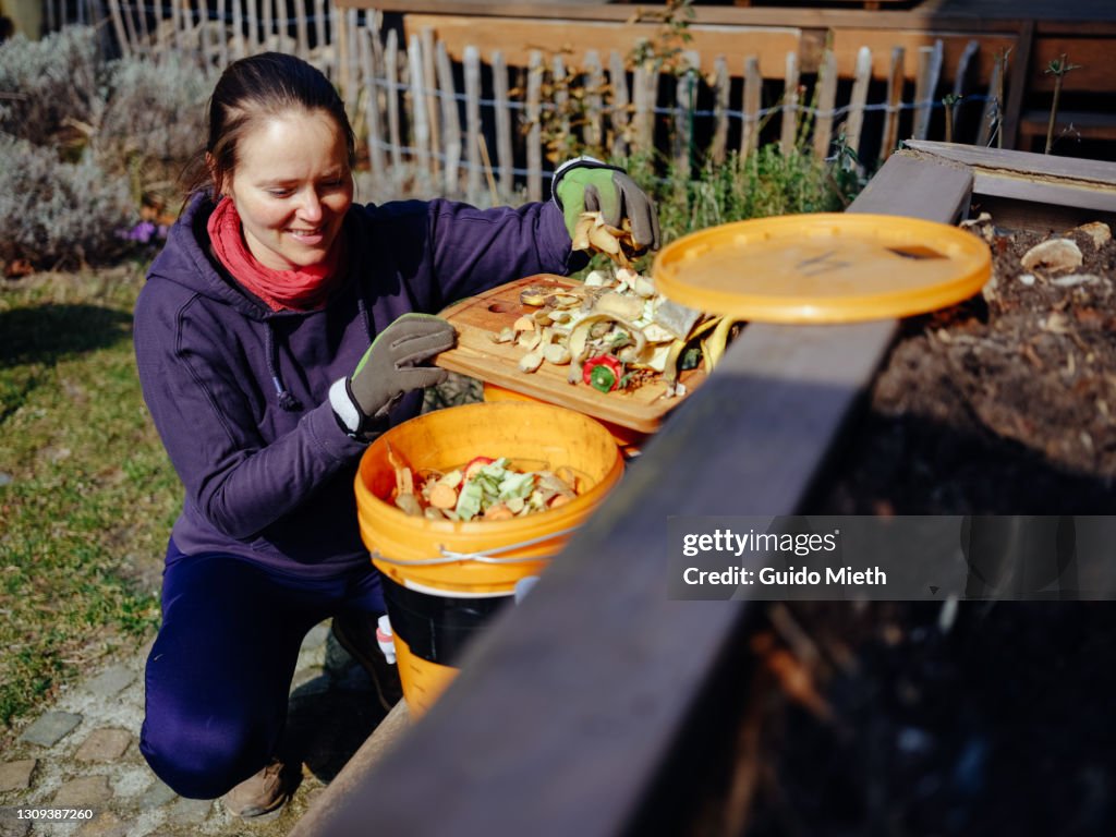 Woman preparing bio waste and microorganism dilution using diy bokashi bucket.