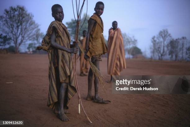 Sudanese refugee boys, one holding stripped branches of wood, pictured at an abandoned mission near Palotaka, South Sudan, two hundred kilometres...