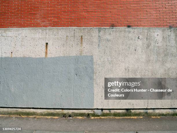 old brick and concrete wall with blue paint and sidewalk in paris - city wall stock-fotos und bilder