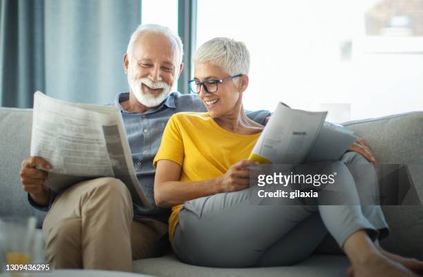 mature couple reading magazines and having a conversation. - old man looking down stock pictures, royalty-free photos & images