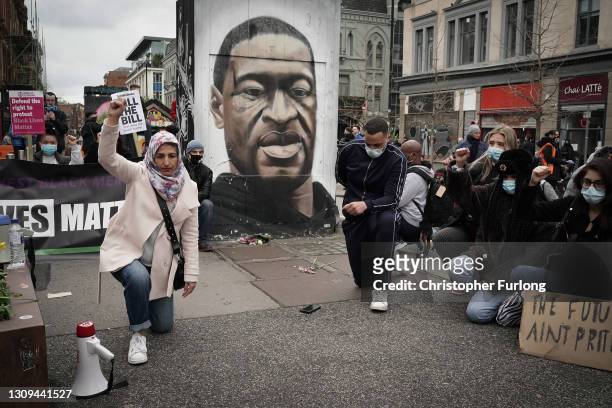 Demonstrators kneel in front of a mural depicting George Floyd during a "Kill the Bill" protest in Manchester City Centre on March 27, 2021 in...