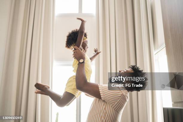father holding daughter up in the air at home - kid throwing stock pictures, royalty-free photos & images