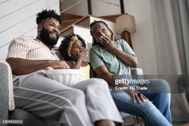 familia comiendo palomitas de maíz y viendo la televisión en casa - reality tv fotografías e imágenes de stock