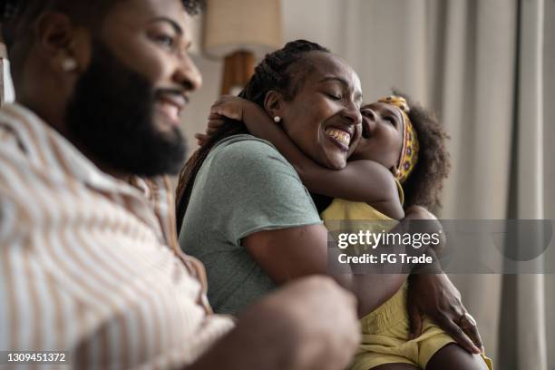 cute girl embracing mother at home - mother father daughter stock pictures, royalty-free photos & images