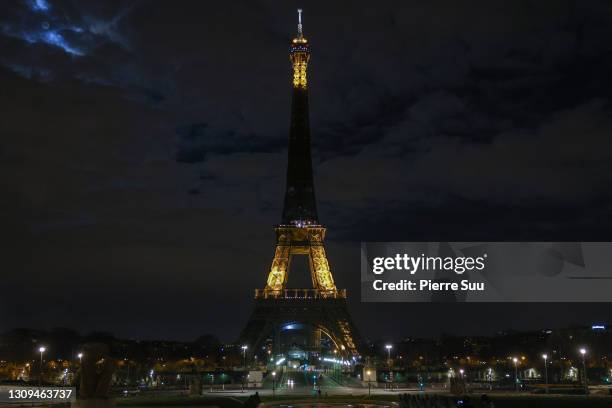 The Eiffel Tower submerges into darkness as part of the Earth Hour switch-off on March 27, 2021 in Paris, France. On the initiative of the World Wide...