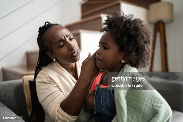 mother is checking her daughter's temperature at home - hot latino girl imagens e fotografias de stock