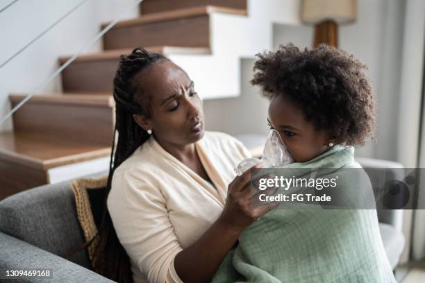 mother helping daughter using nebulizer during inhalation therapy - asthma inhaler child stock pictures, royalty-free photos & images