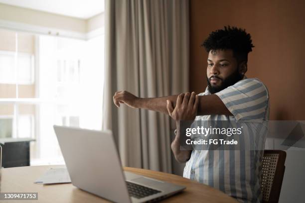 young man stretching while working at home - stretching at work stock pictures, royalty-free photos & images