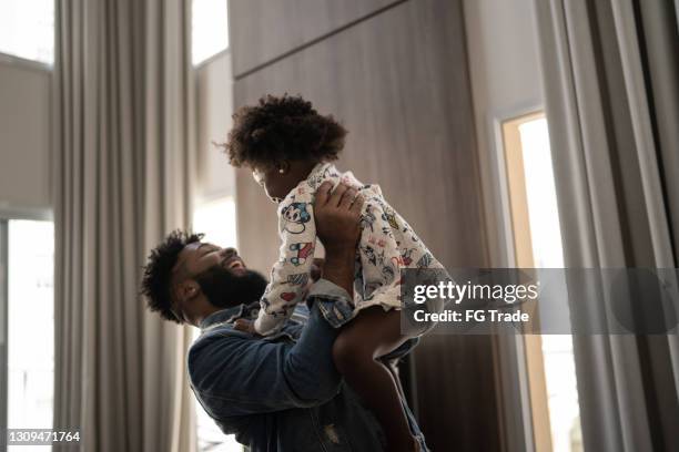 father holding daughter up in the air at home - dad throwing kid in air imagens e fotografias de stock