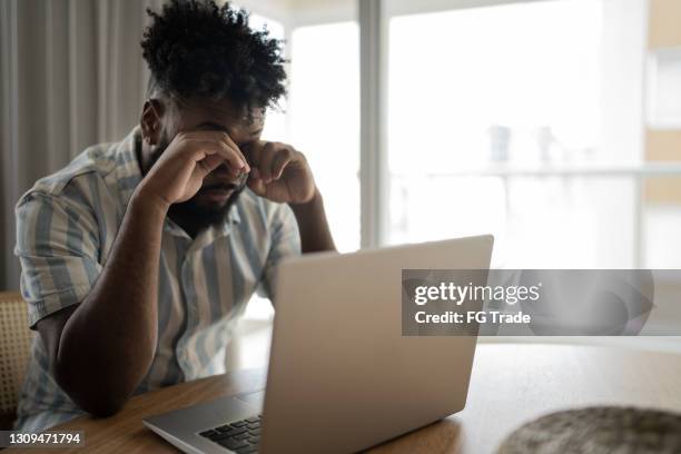 tired man rubbing eyes working at home - conjunctivitis stock pictures, royalty-free photos & images