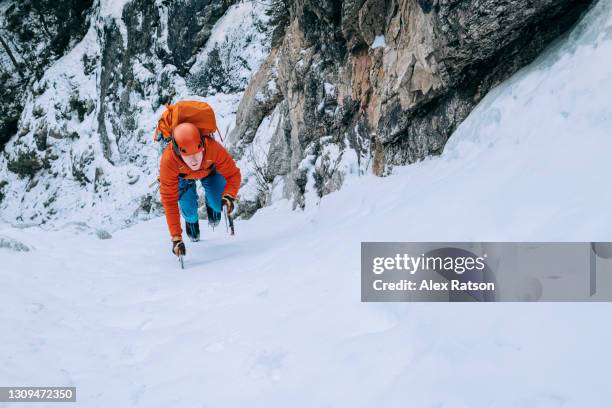 ice climber quickly climbs up a low angle sow gully with ice axes and crampons - crampon stock pictures, royalty-free photos & images