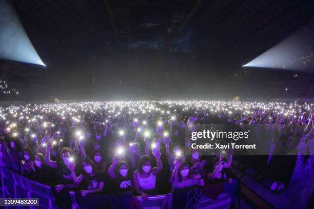 Audience members light up with their phones and wear face masks during the Love of Lesbian's concert at Palau Sant Jordi on March 27, 2021 in...