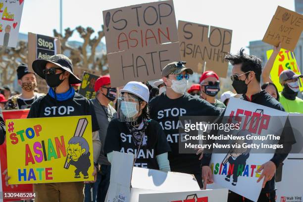 William Guo, left, Francis Kwok, Henry Lei, right, all of Alameda, and about a thousand demonstrators listen to speakers during an anti-Asian...