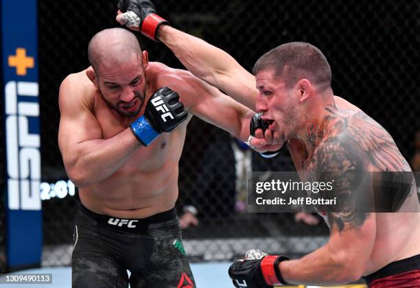 Abu Azaitar of Morocco punches Marc-Andre Barriault of Canada in their middleweight fight during the UFC 260 event at UFC APEX on March 27, 2021 in...