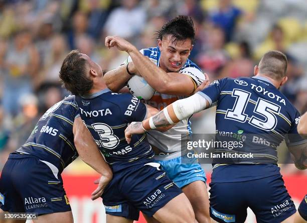 Tino Fa'asuamaleaui of the Titans is tackled by Reuben Cotter and Josh McGuire of the Cowboys during the round three NRL match between the North...