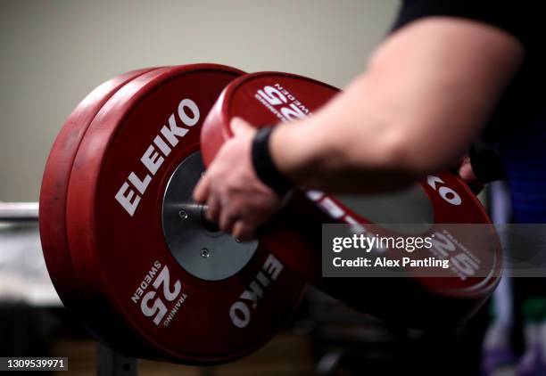 Nakatsuji Katsuhito of Japan places weights onto the bar as he warms up in the practice area ahead of the Men's up to 107kg during day four of the...