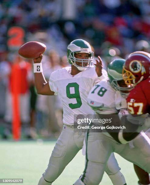 Quarterback Rodney Peete of the Philadelphia Eagles passes as offensive lineman Antone Davis blocks linebacker Ken Harvey of the Washington Redskins...