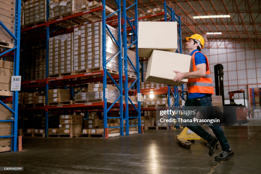 A worker in a warehouse tripping over a broken pallet