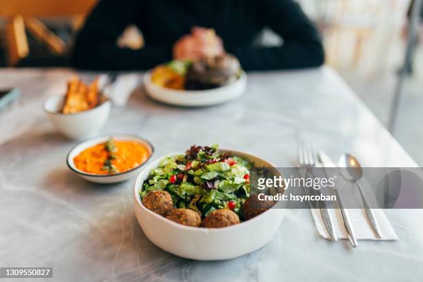 mujer comiendo falafel en un restaurante - faláfel fotografías e imágenes de stock