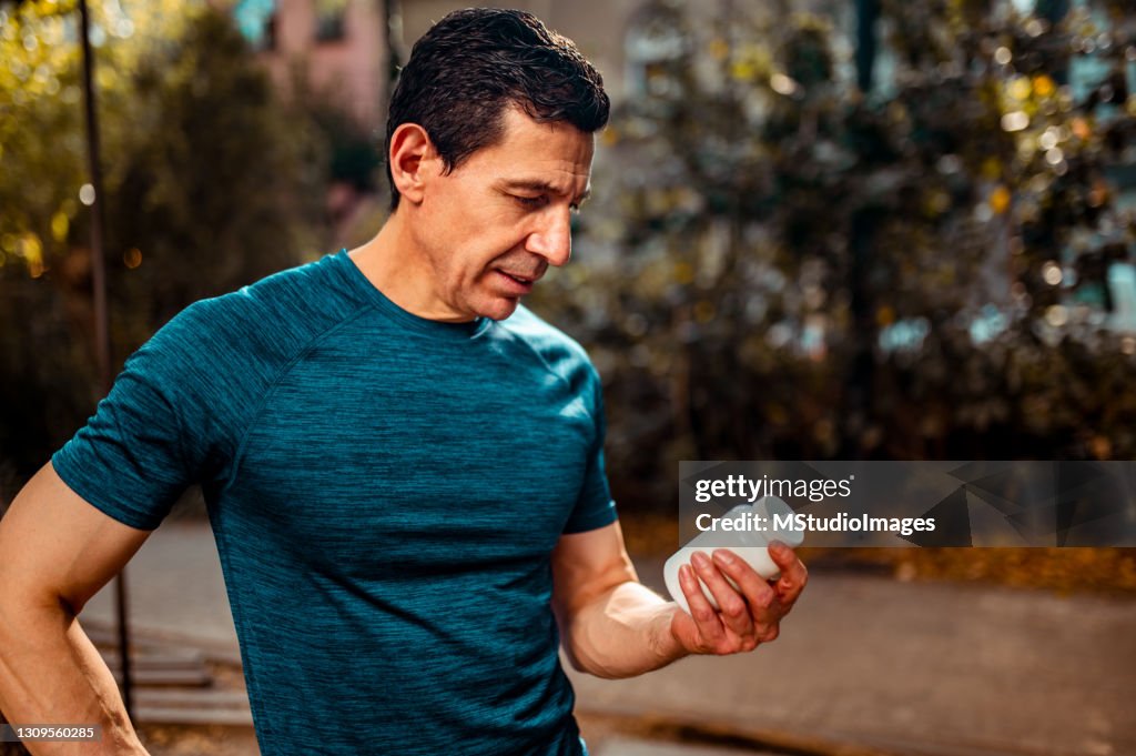 The athlete looks at the bottle of medicine