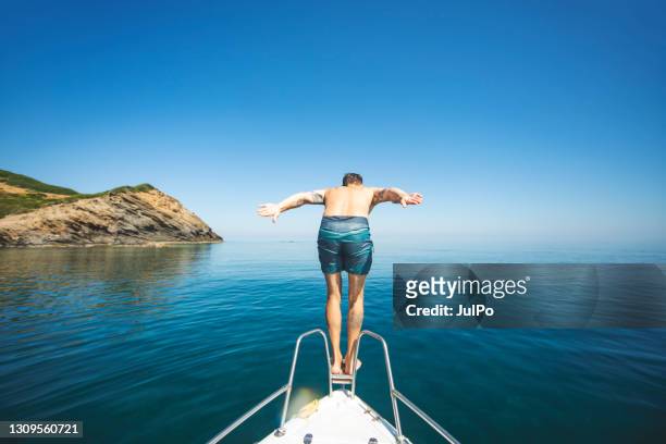 jeune homme adulte plongeant de son yacht - jumping of boat photos et images de collection