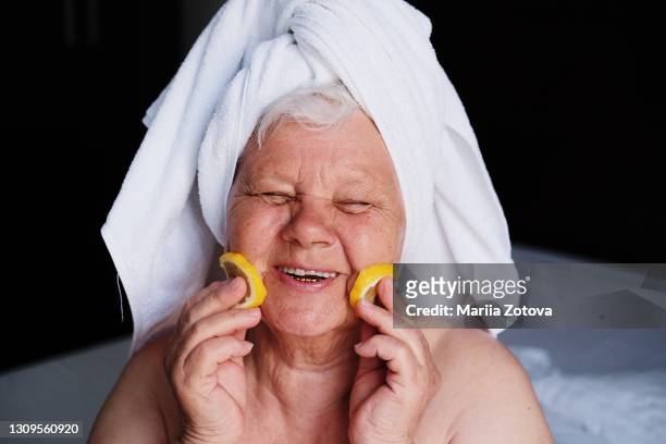portrait of a cheerful old lady who laughs and enjoys life, takes wellness beauty treatments at home - irony stock-fotos und bilder