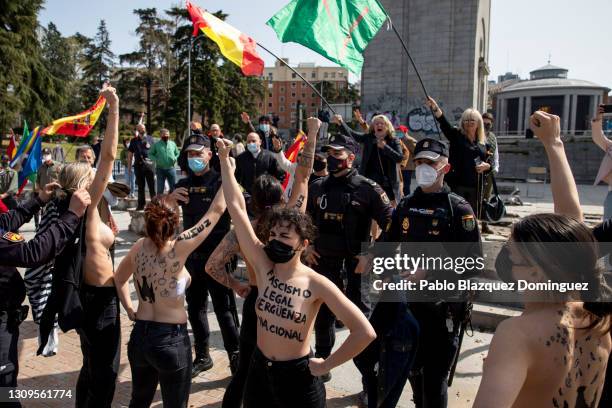 Activist with body paint reading 'To fascism neither honor, nor glory.' raise their fists, as Franco supporters do a fascist salute in the back...