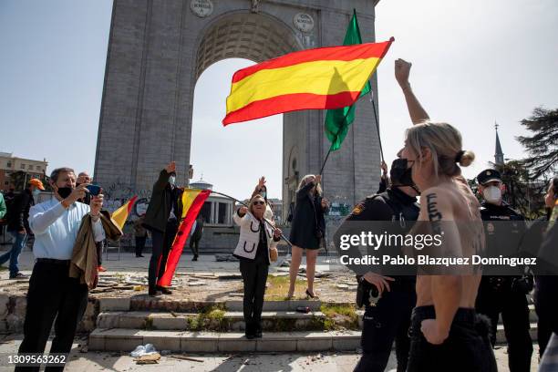 Activist with body paint raises her fist, as Franco supporters do a fascist salute in the back during a gathering of right-wing supporters at Arco de...