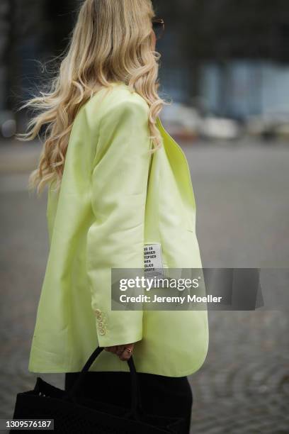 Martina Maturi wearing neon yellow H&M Studio blazer, black pants and black Dior tote bag on March 25, 2021 in Cologne, Germany.