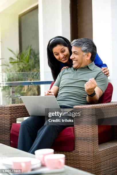 couple celebrating online success using laptop - 40 49 years stock pictures, royalty-free photos & images