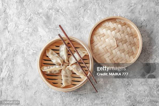 steamed chinese dumplings (jiaozi) on bamboo steamer and chopsticks, concrete background, top view - dim sum stock-fotos und bilder