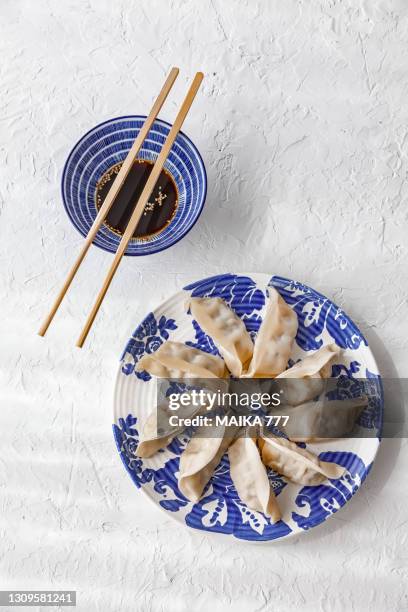 gyozas (japanese dumplings) on plate, chopsticks and sauce, white background, top view - 点心 ストックフォトと画像