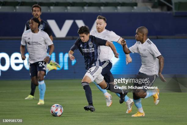 Jonathan Perez of Los Angeles Galaxy takes the ball down field as Lucas Maciel of New England Revolution defends during the first half at Dignity...