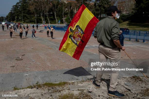 Franco supporter holding a pre-constitutional Spanish flag turns away from FEMEN activists running towards him during a gathering of right-wing...