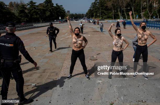 Activist wearing body paint reading 'To fascism neither honor, nor glory.' and 'Legal fascism, national shame.' raise their fists during a gathering...